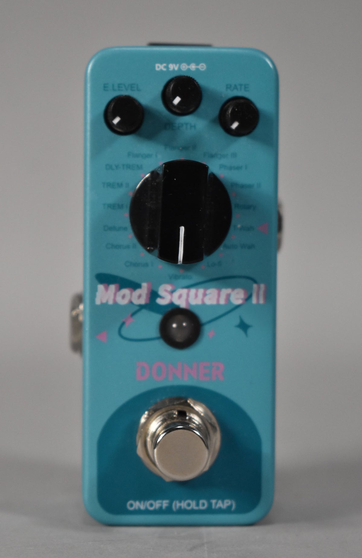 A turquoise pedal with a large central black knob, three smaller black knobs, and a chrome footswitch.