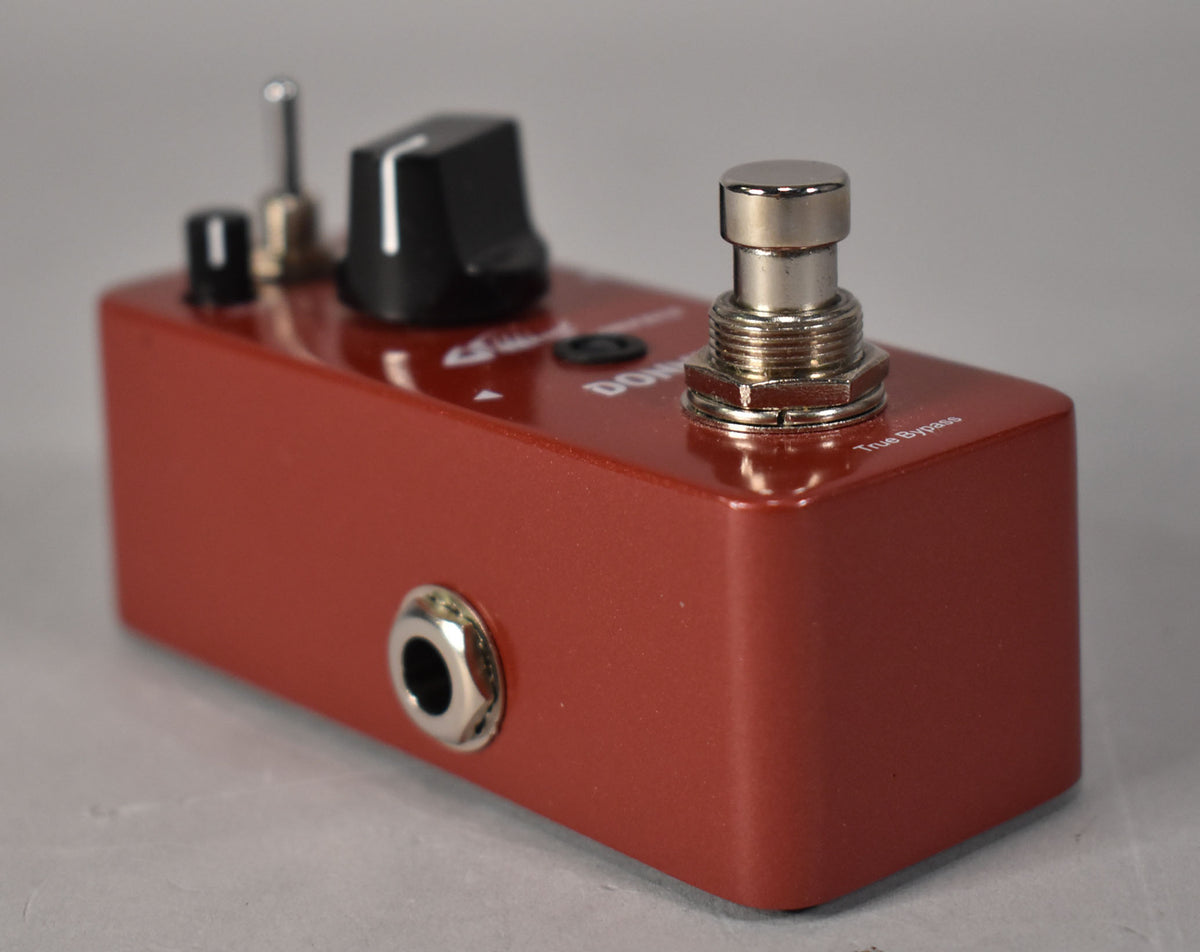The red metal pedal is angled from the right, showing a silver footswitch, a black knob, two small switches, and a jack.