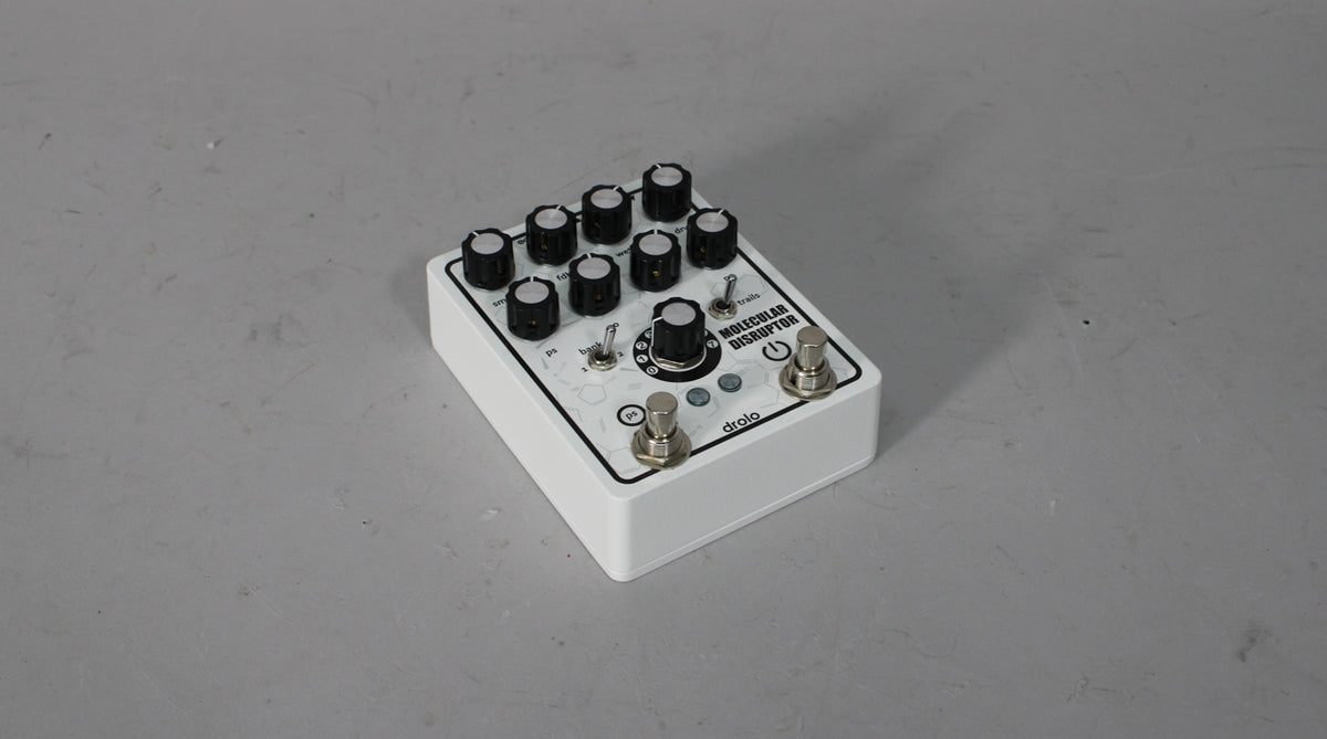 White pedal with black graphics, 8 small black knobs, one large black knob, two toggle switches, and two footswitches.