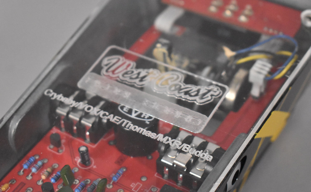 A close-up of the pedal's internal red circuit board, visible through a clear top panel with "West Coast" and "EVH" etched on it.