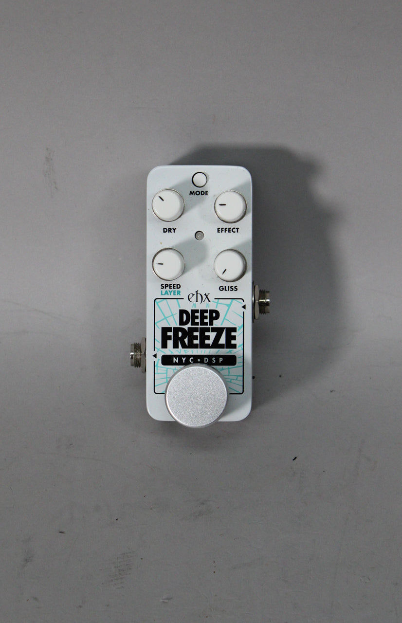 A white guitar pedal with a large silver footswitch, four white control knobs, and two input jacks on the sides.
