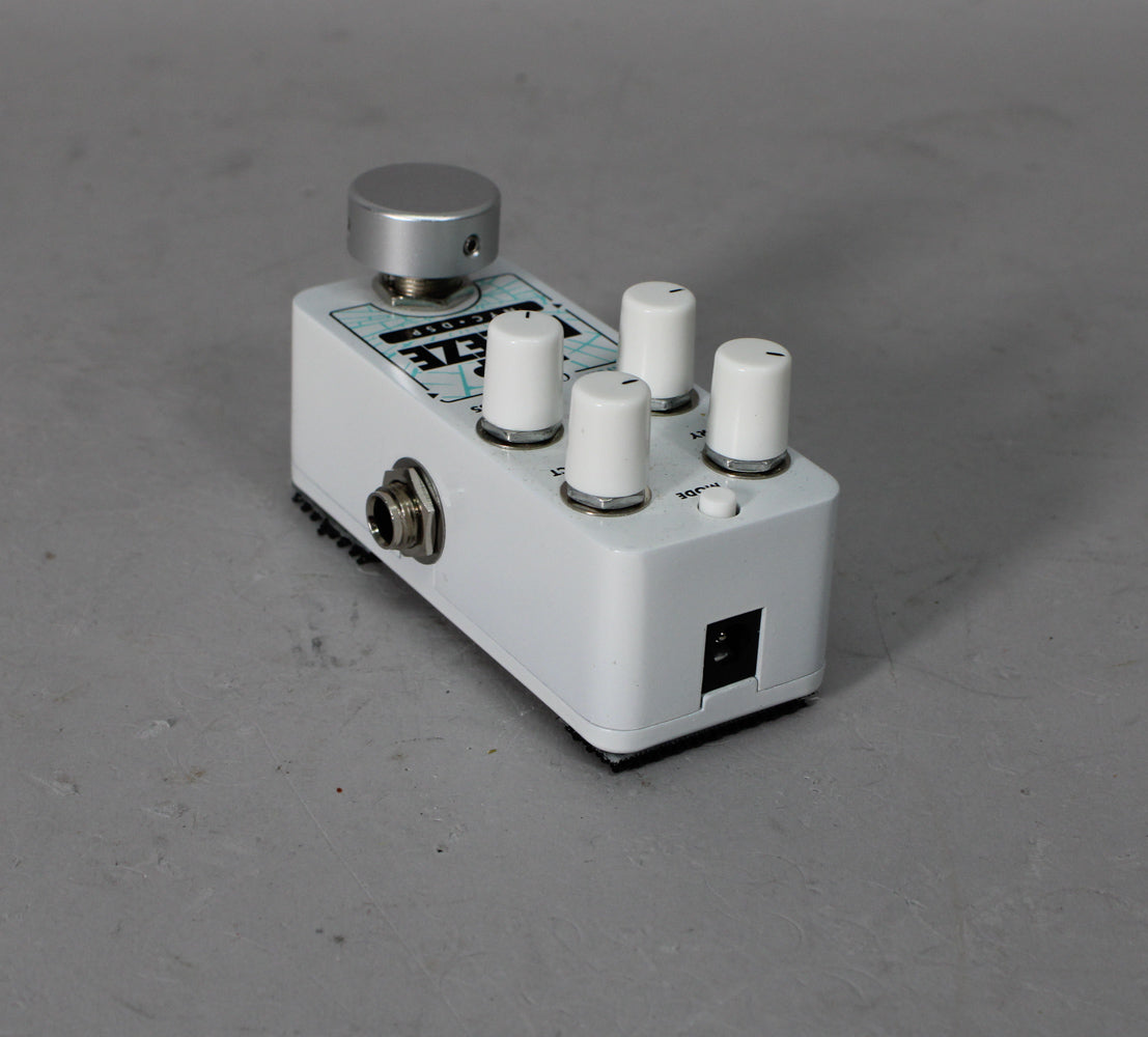 White pedal with a large silver footswitch, four smaller white control knobs, an input jack, and a power input.