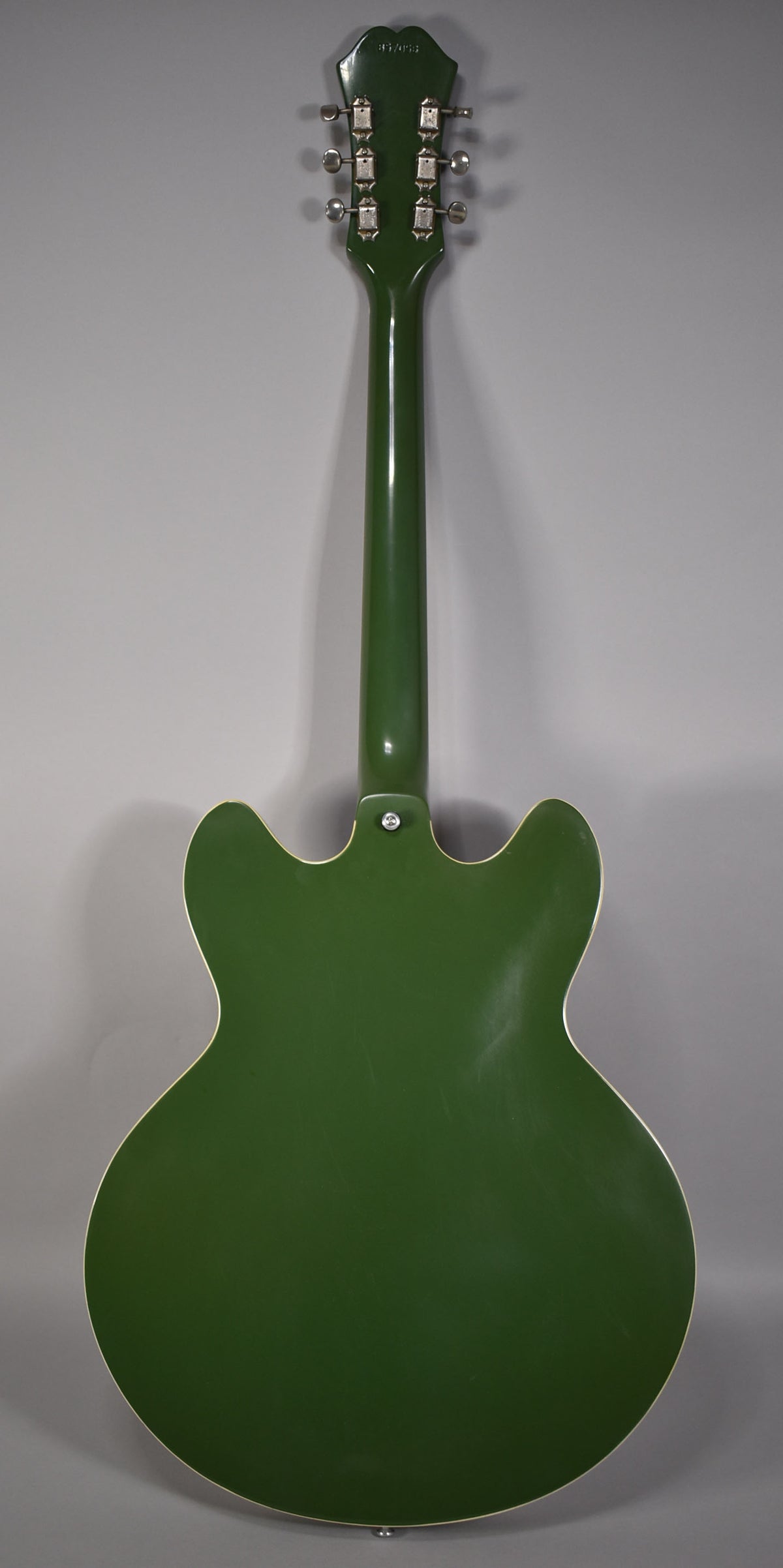 Full back view of an olive drab hollowbody guitar with a glossy finish, showing six chrome tuners and light surface wear.
