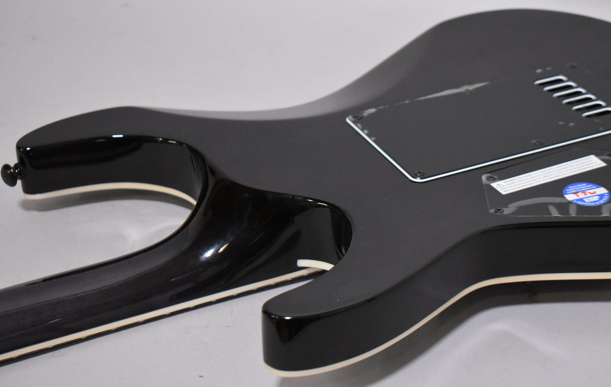 The guitar's charcoal burst body, with cream binding, is seen from the back, showing the neck joint and control cavity cover.