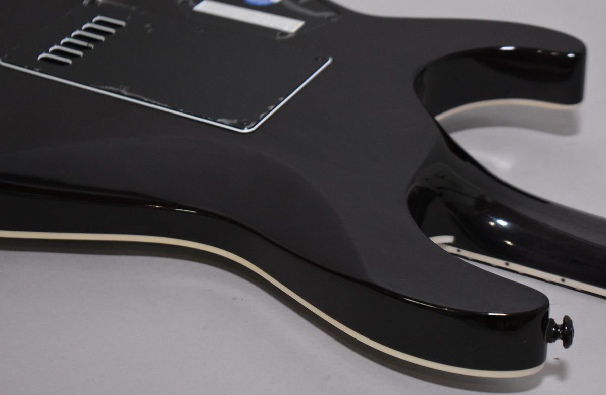 The back of a charcoal burst guitar, showing the control cavity cover, neck joint, and a black strap button.