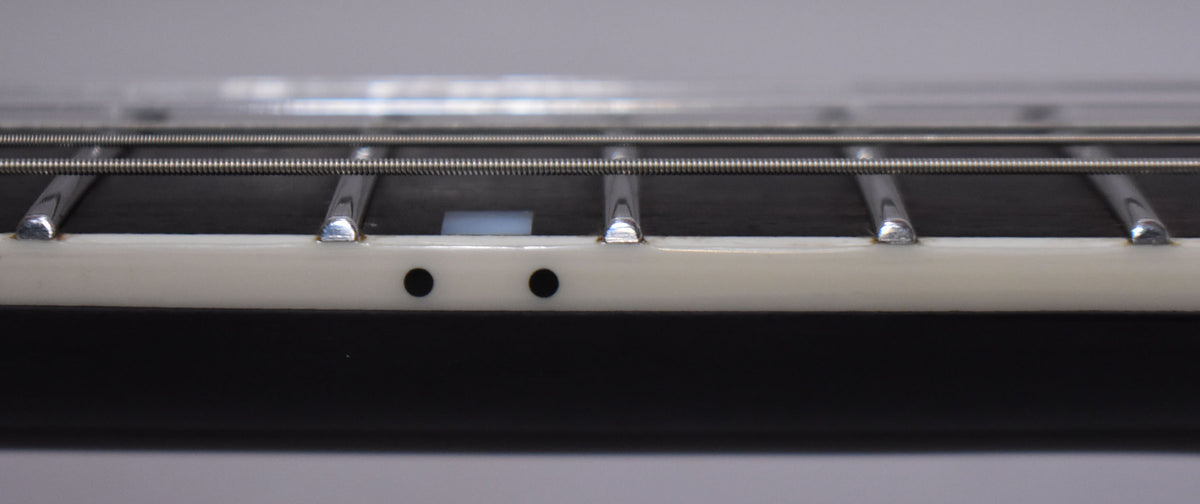 Close-up of the guitar's fretboard, showing two black side dots and a rectangular white inlay between the frets.