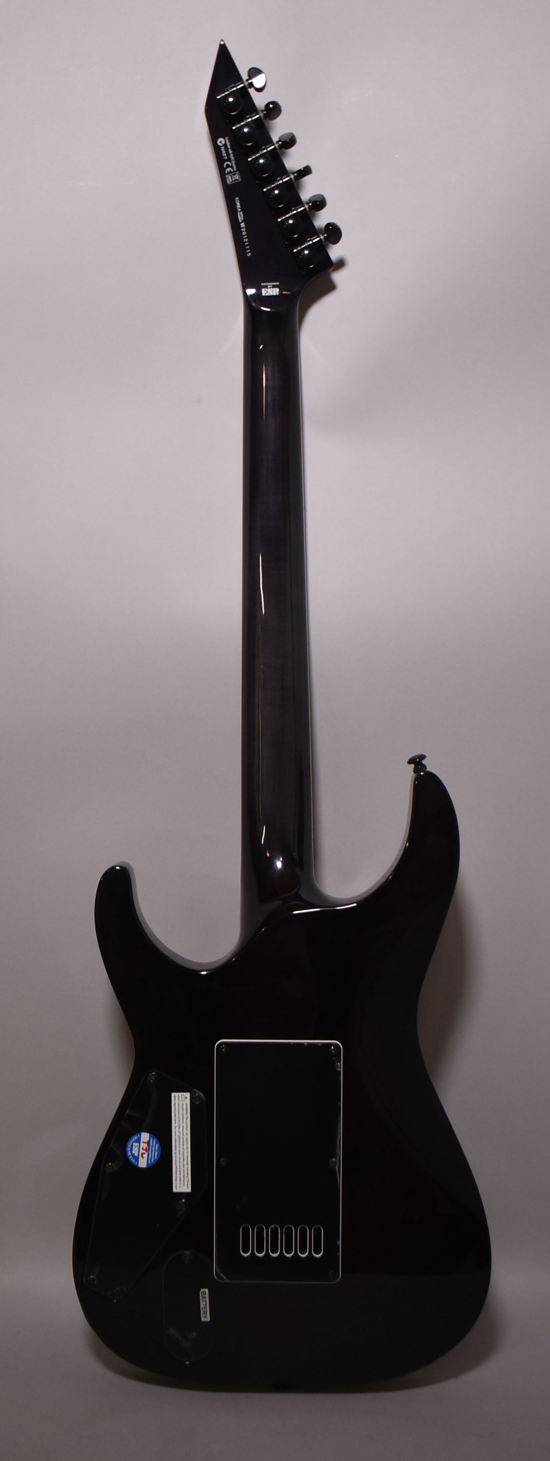 Full rear view of a dark charcoal burst electric guitar with a glossy finish, black hardware, and a rectangular control cavity cover.