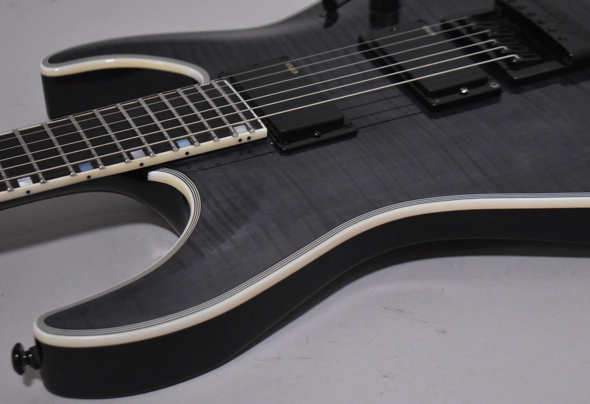 The charcoal burst guitar body, with cream binding, shows a dark grey flamed maple top and black EverTune bridge.