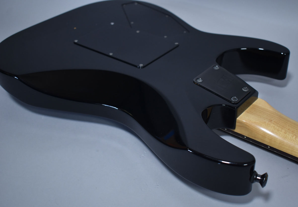 The guitar's glossy black back is angled, revealing a light wood neck and black neck plate, with two control cavity covers.
