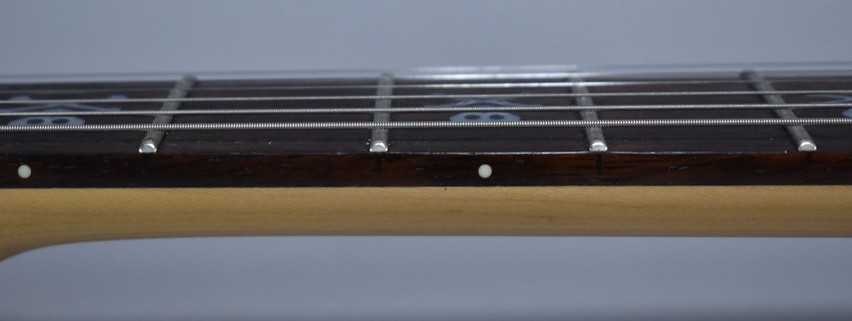 Close-up of the dark fretboard and light maple neck, showing the frets, strings, and skull-and-crossbones inlays.