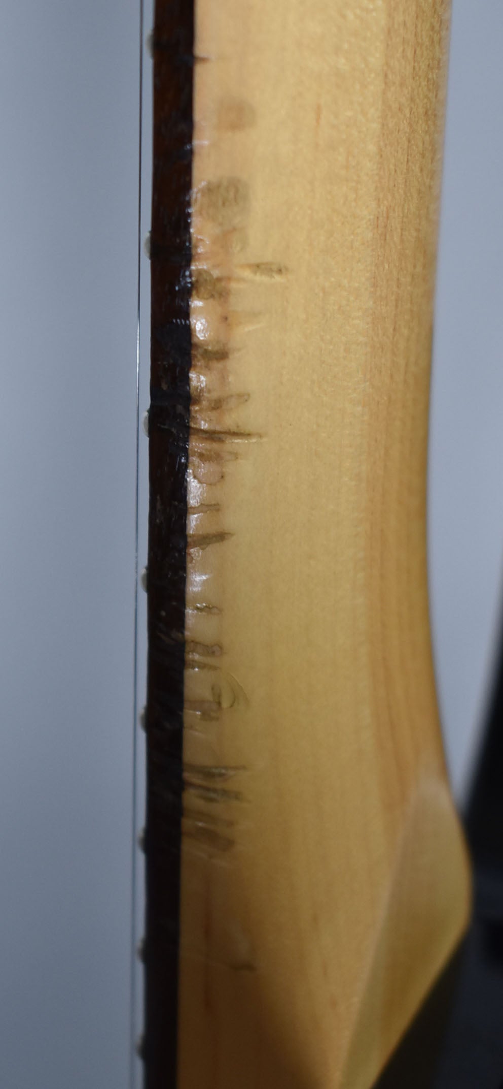 Close-up of the guitar's neck, showing the light-colored wood with dark finish wear along the fretboard edge.