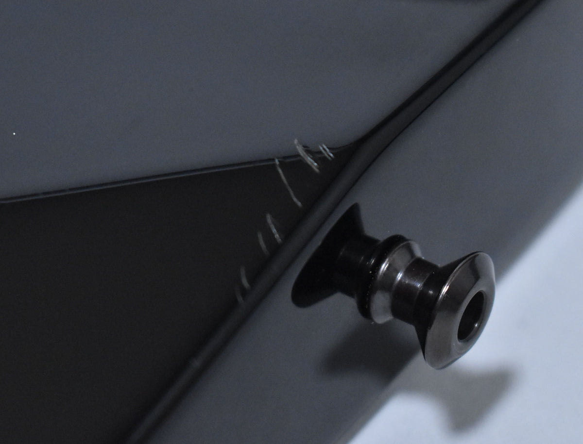 Close-up of the guitar's black gloss body near the strap button, showing several light scratches on the finish.