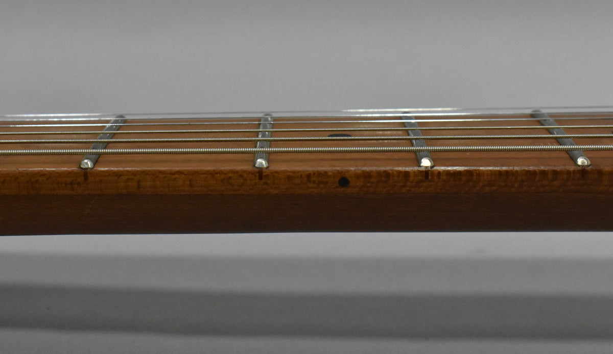 Close-up of the guitar's fretboard, showing the side dots and frets from the 1st to the 6th, with a dark brown satin finish.