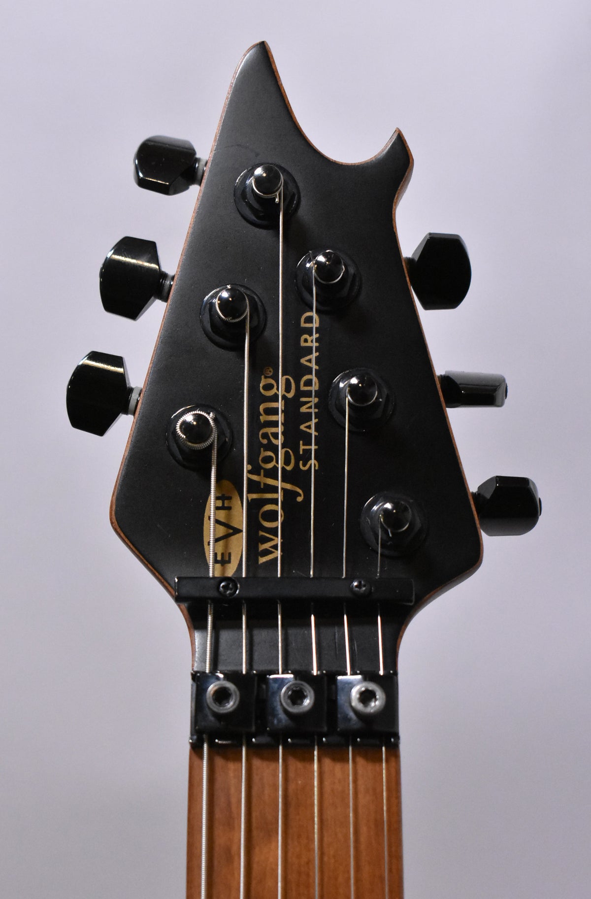 Close-up of the satin black headstock with six black tuners, a locking nut, and a visible natural wood neck.