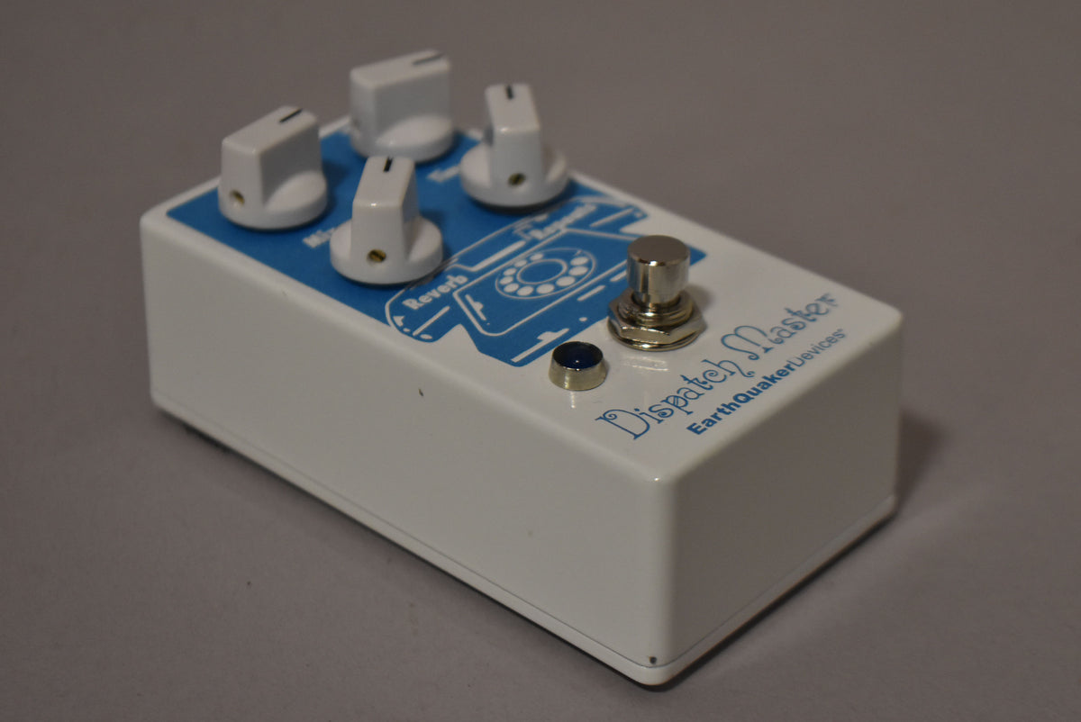 The white pedal is angled from the left, showing its top with four white knobs, a blue LED, and a silver footswitch.