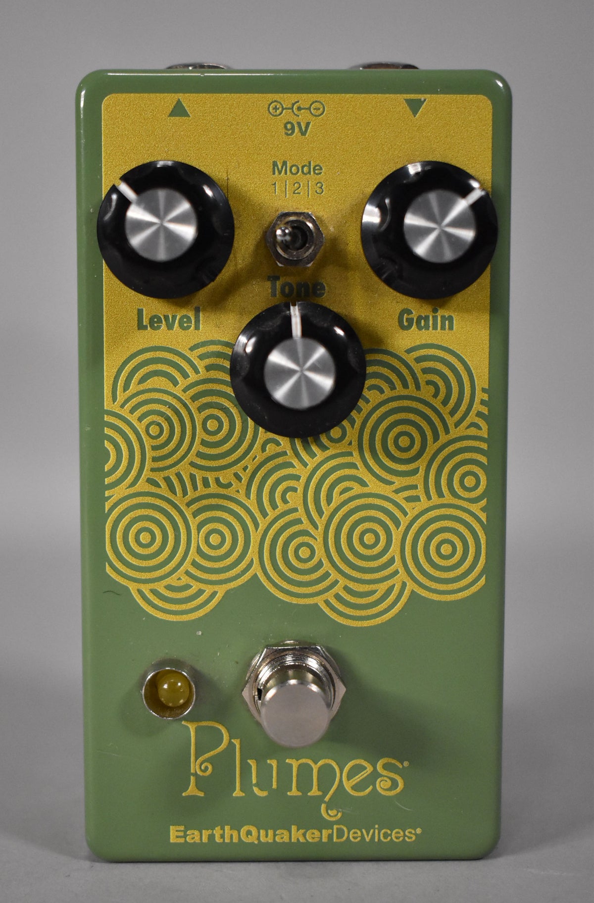A green pedal with a gold faceplate featuring three black knobs, a small toggle switch, a footswitch, and a yellow LED.