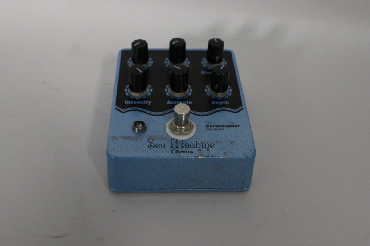 Light blue pedal, angled from the right, showing six black control knobs, a footswitch, and some scuffs on the top surface.