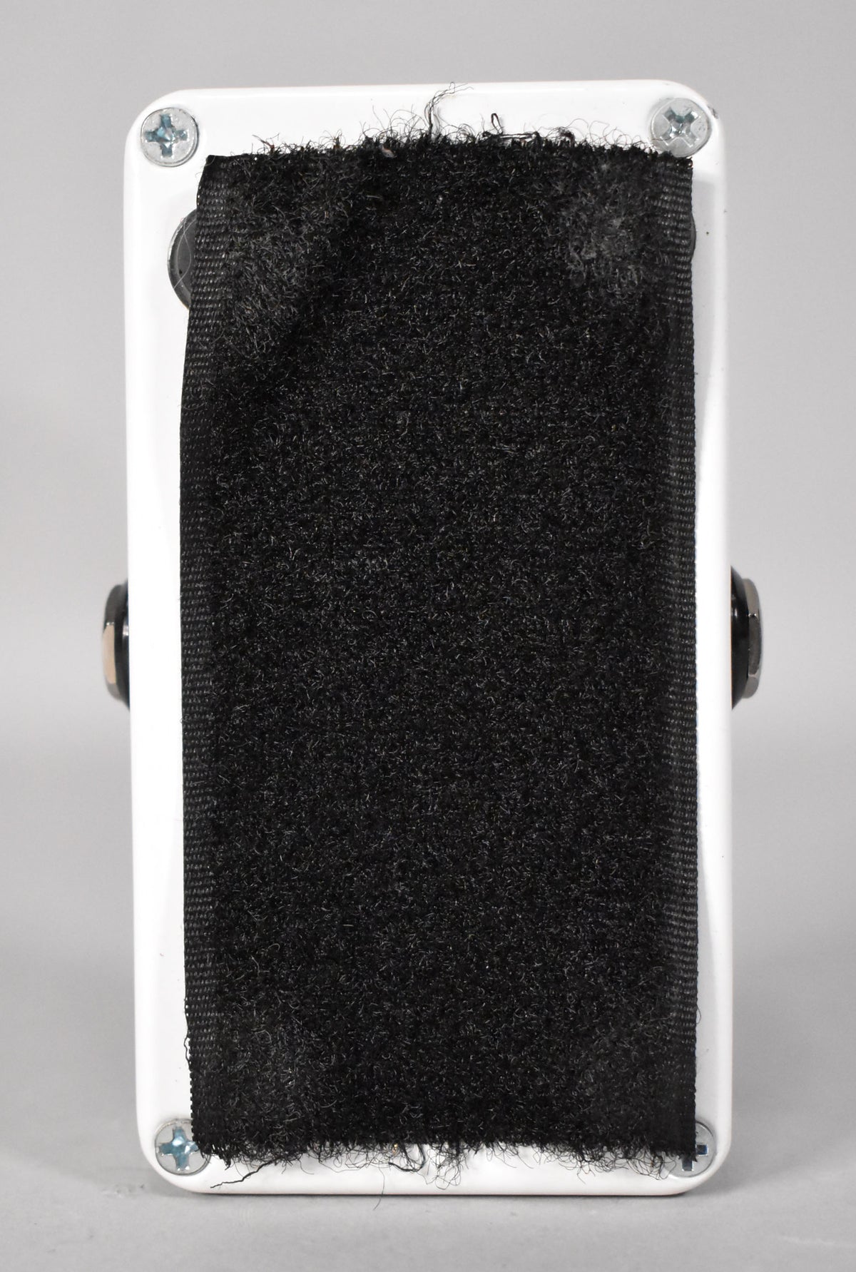 The pedal's white underside is covered with black hook-and-loop fastener, secured by four silver Phillips head screws.
