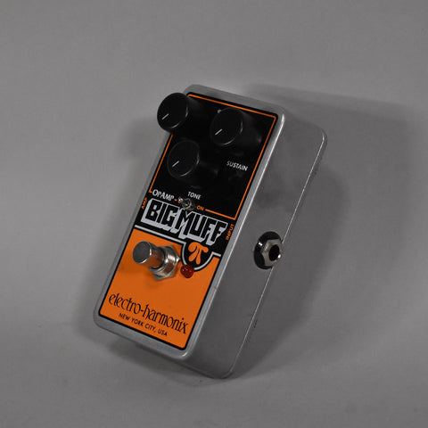 A silver guitar pedal with an orange and black faceplate, four black knobs, a silver footswitch, and a red indicator light.