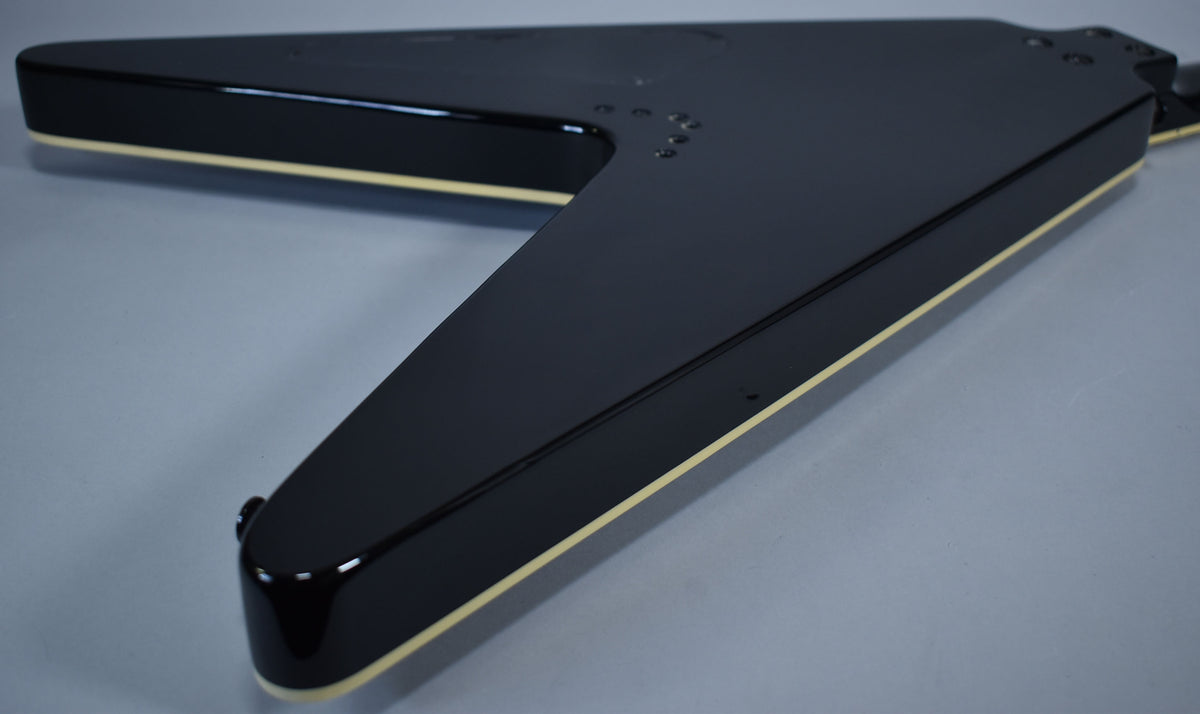 The back of the glossy black Flying V body, showing cream binding along the edges and a few small dings near the neck joint.