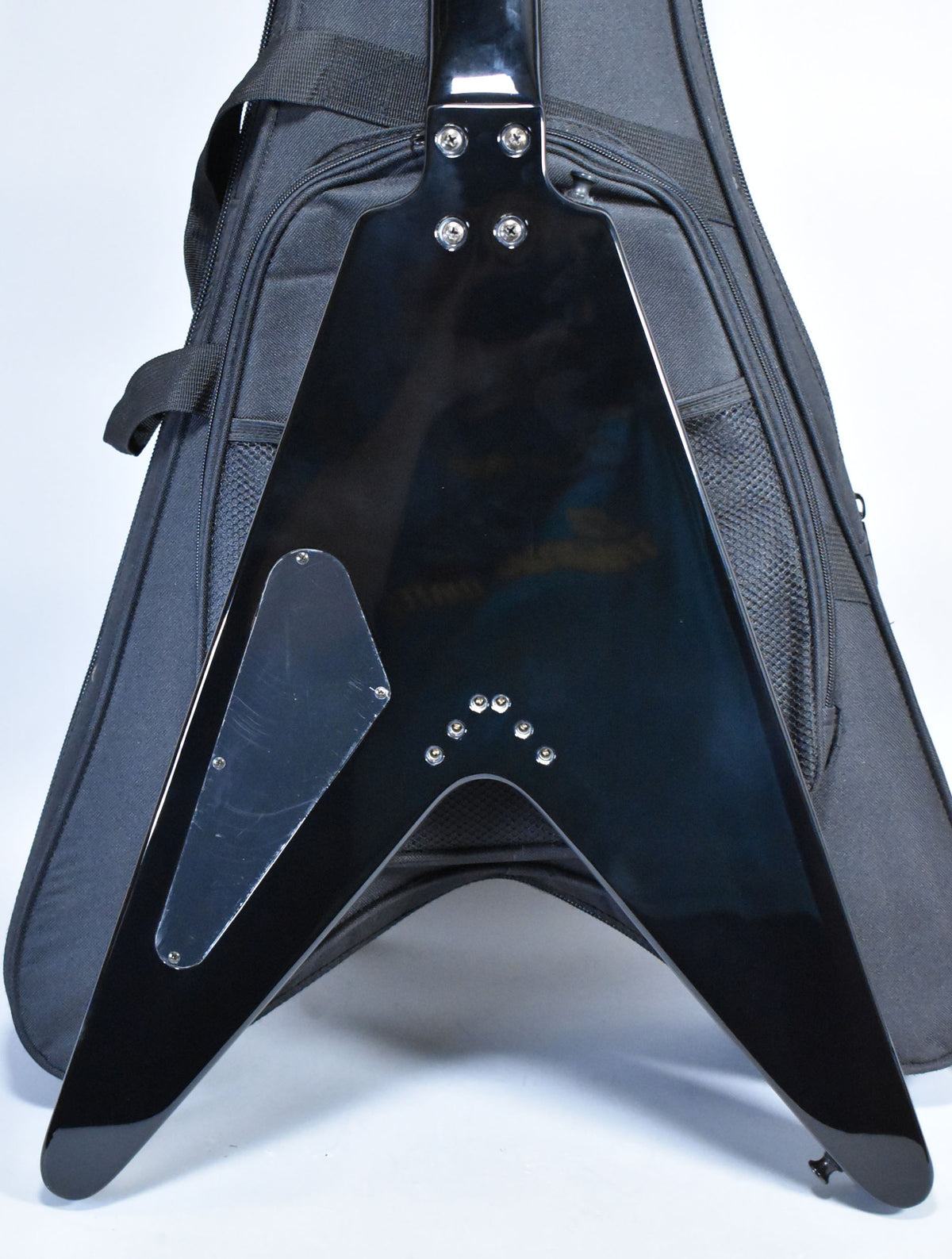 Rear view of a glossy black Flying V electric guitar, showing the neck plate, control cavity cover, and string ferrules.