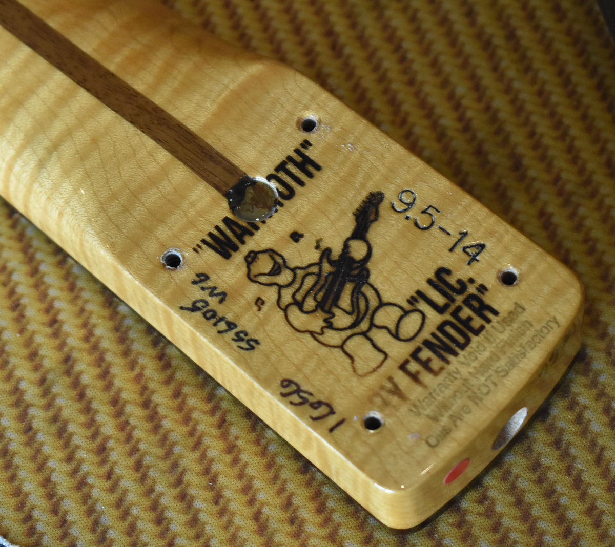 Close-up of the light maple neck heel with a dark wood skunk stripe, showing stamped and handwritten markings.