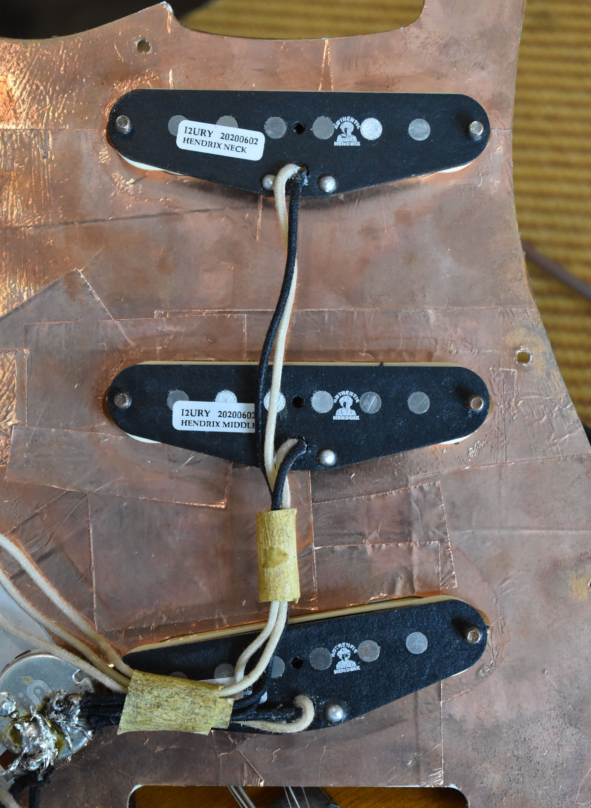 The guitar body's interior is lined with copper foil, revealing three black single-coil pickups with white bobbins and wiring.