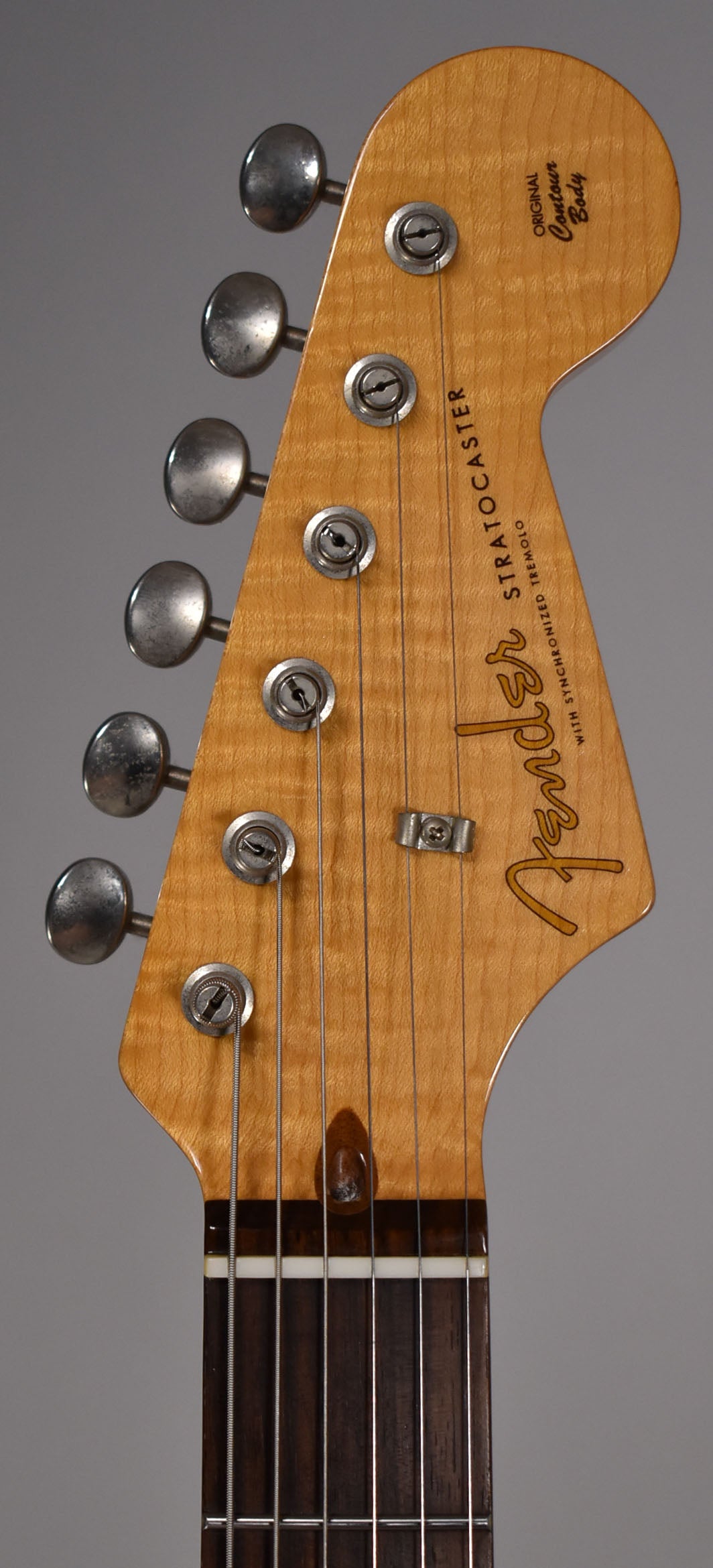 Close-up of a light maple headstock with six tarnished tuners, a string tree, and a dark rosewood fretboard.