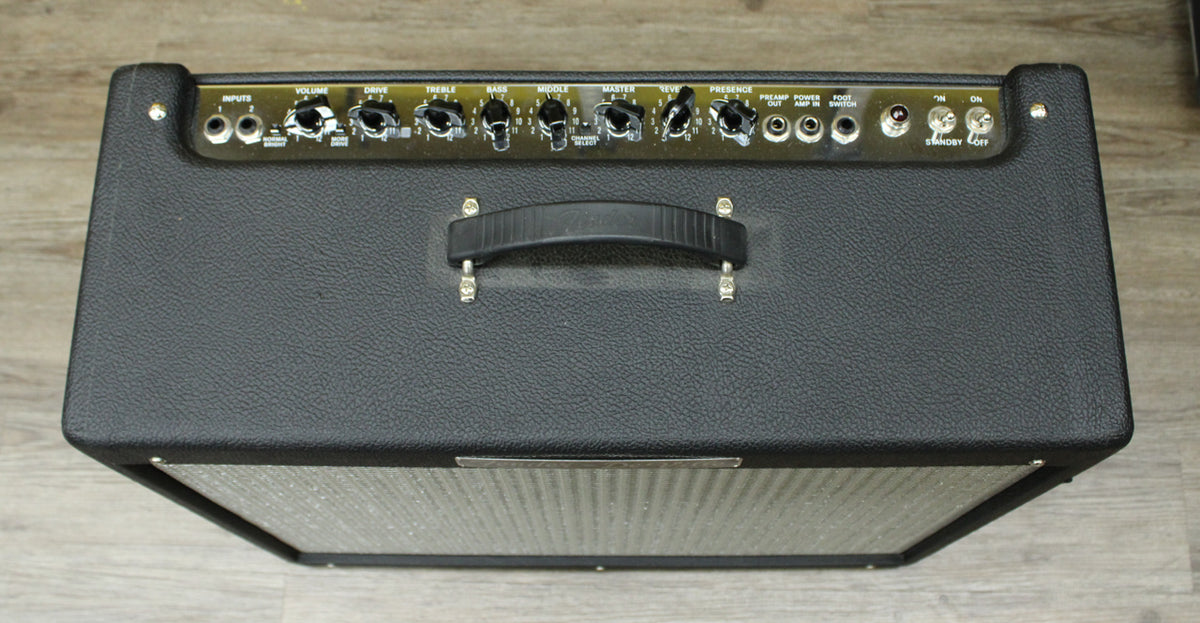 Top-down view of the black textured combo amp, showing the full control panel with black knobs and a central black handle.
