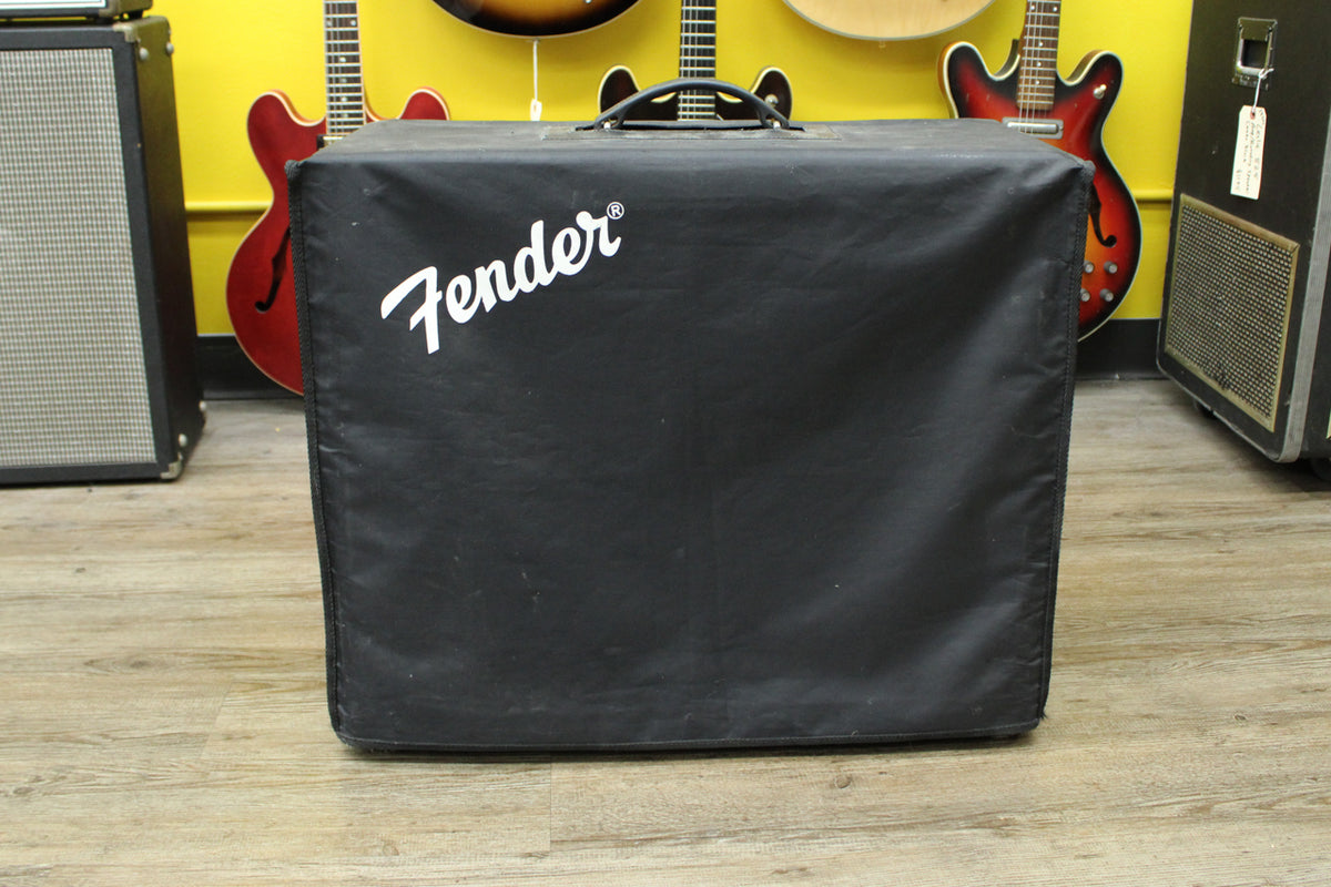 Full front view of the black vinyl amp cover with a white script logo, showing a top handle and some dust.