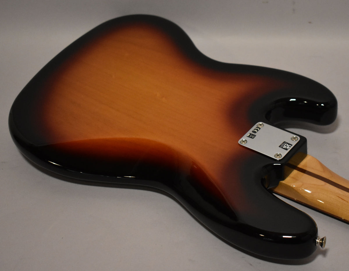 The back of a sunburst bass guitar, showing the glossy finish, chrome neck plate, and a small portion of the maple neck.