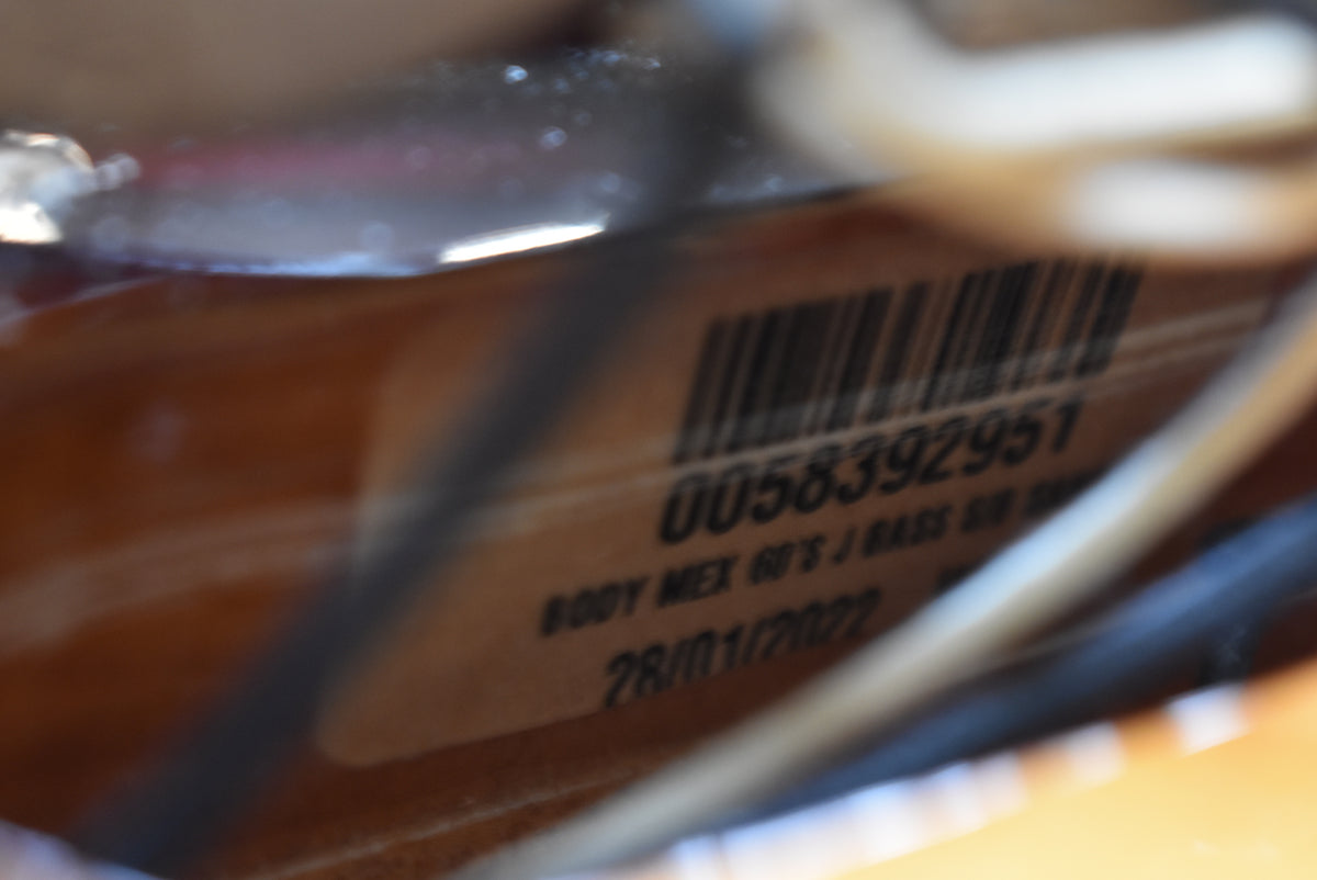 Close-up of a sticker with a barcode and text "0058392951 BODY MEX 60'S J BASS BB 28/01/2022" on the sunburst body.