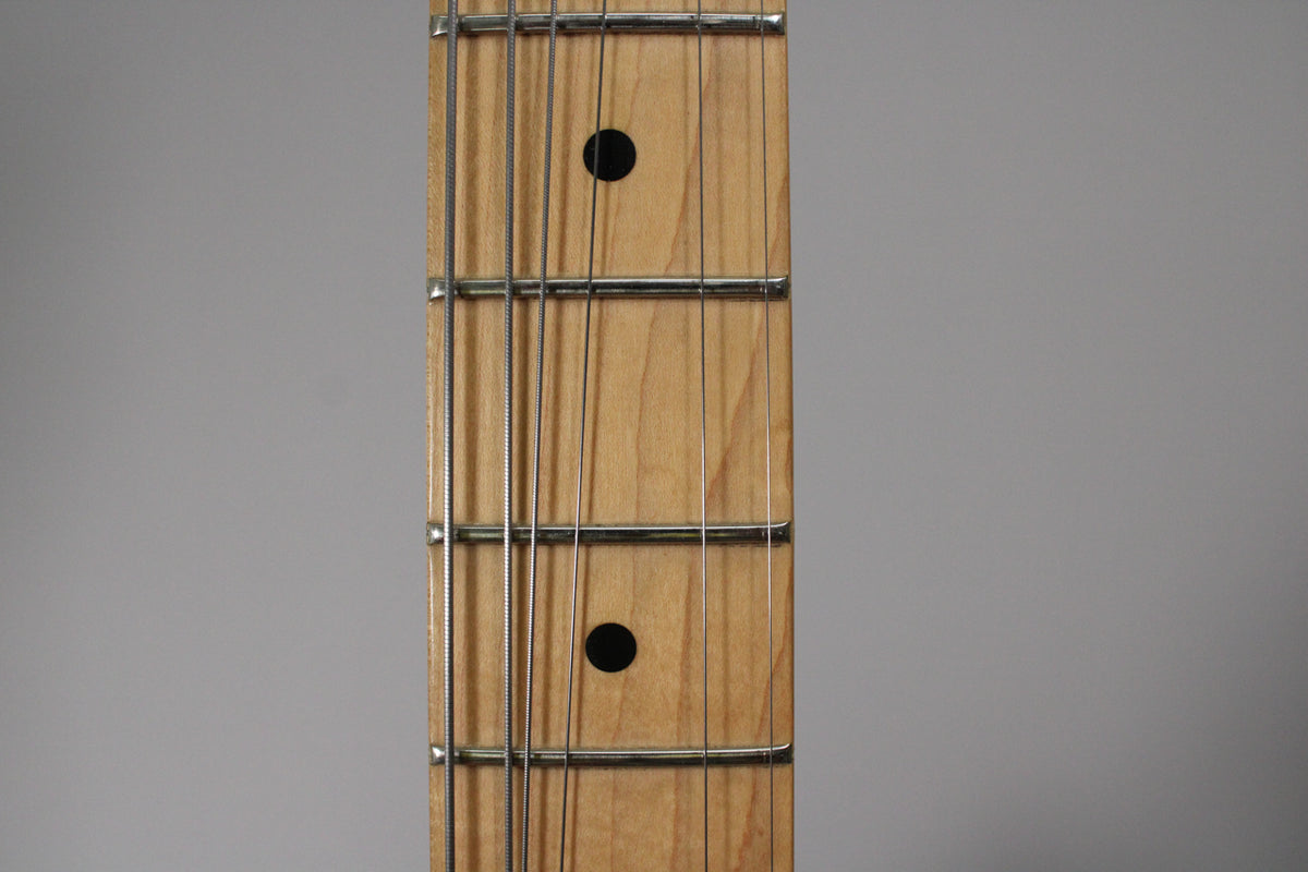 Close-up of the maple fretboard, showing frets 5 through 8, with black dot inlays at the 5th and 7th frets.