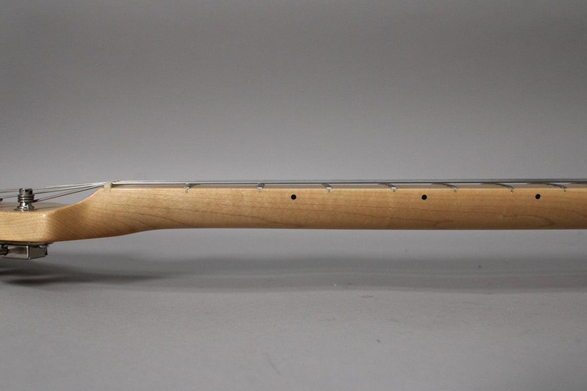 The guitar's light maple neck and fretboard are shown from the side, with dark dot inlays and minimal fret wear visible.