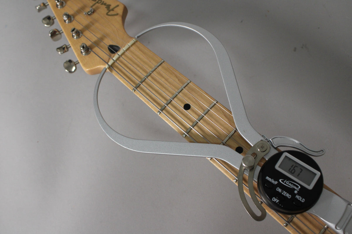 A digital caliper measures the maple fretboard and frets, showing 1.67mm, with the headstock and tuners visible at the top.
