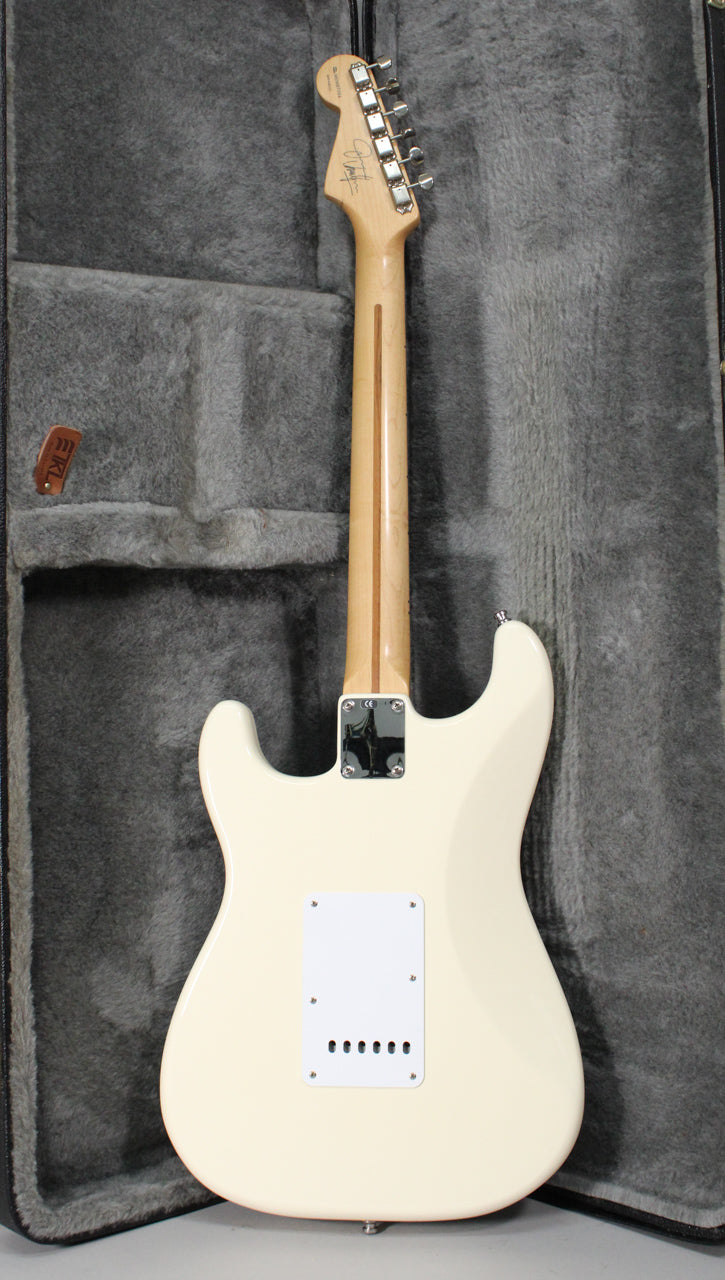 The back of an Olympic White Stratocaster with a maple neck and a white tremolo cover, shown in a grey plush hard case.