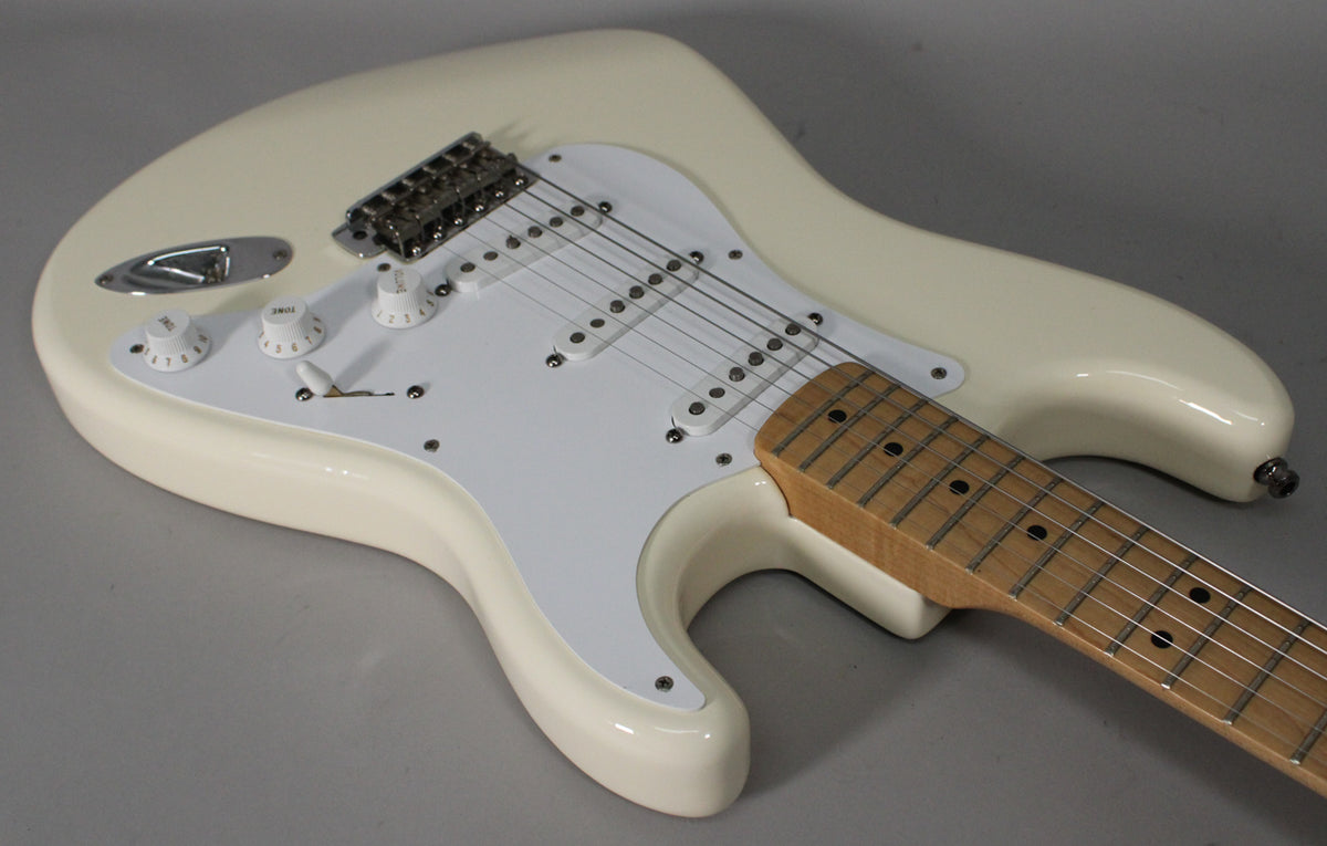An Olympic White Stratocaster, angled from the lower bout, shows its maple fretboard, white pickguard, three single-coil pickups, and chrome hardware.