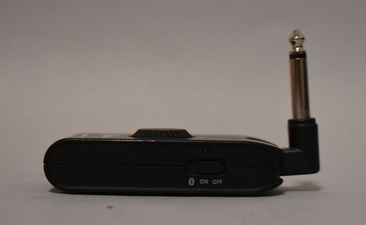 Side view of the black headphone amp, showing a textured control knob, a power switch, and a silver 1/4" jack.