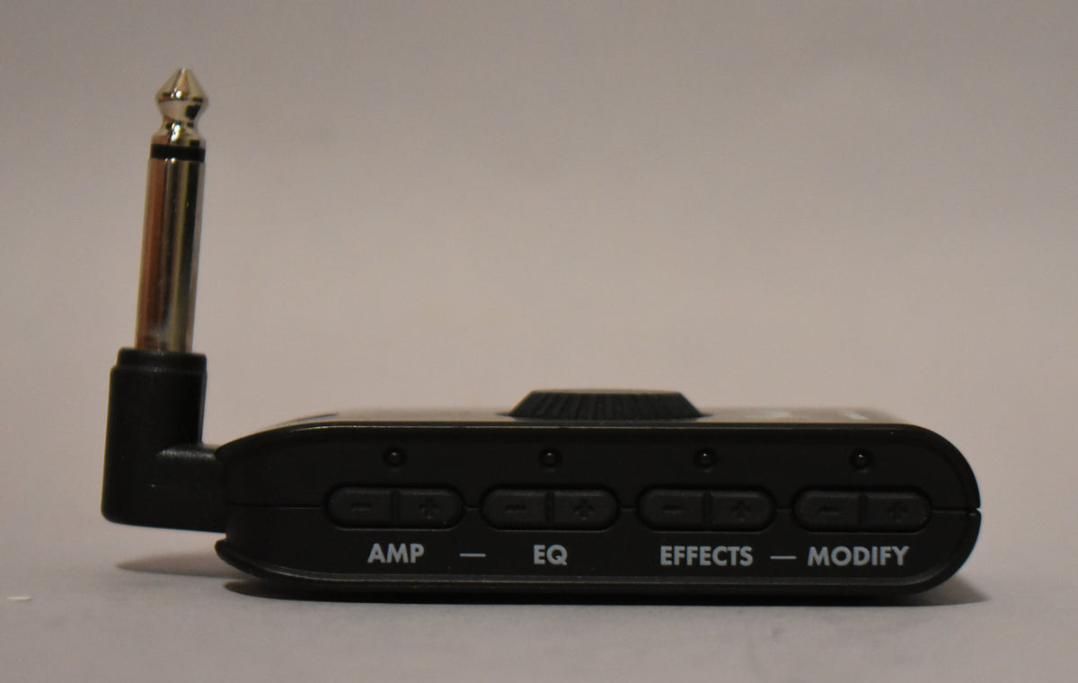 The black headphone amp is viewed from the side, showing a chrome jack and four pairs of control buttons labeled AMP, EQ, EFFECTS, and MODIFY.
