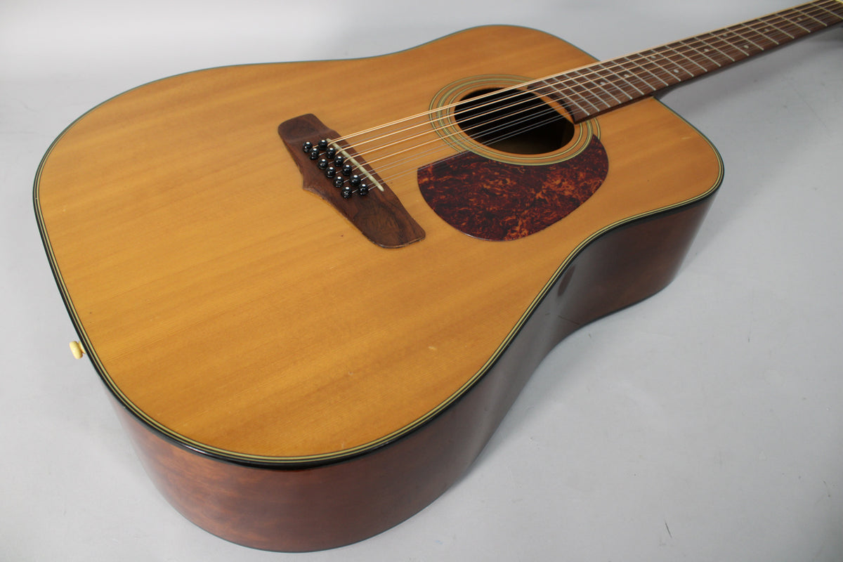 The acoustic guitar's light wood top and dark sides are angled from the lower left, showing the bridge, pickguard, and soundhole.