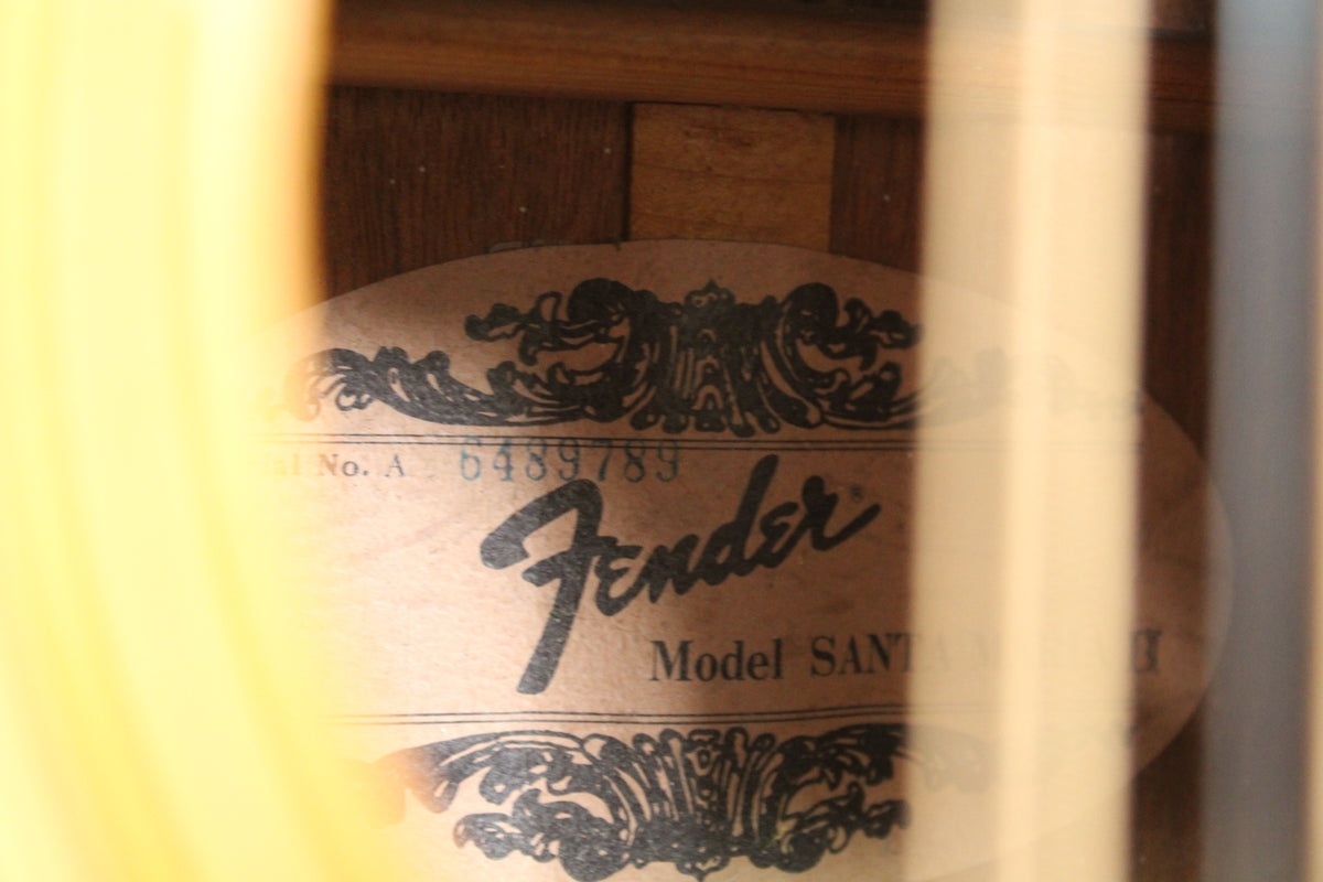 A close-up of the guitar's interior label, showing a faded Fender logo and serial number, partially obscured by light-colored bracing.