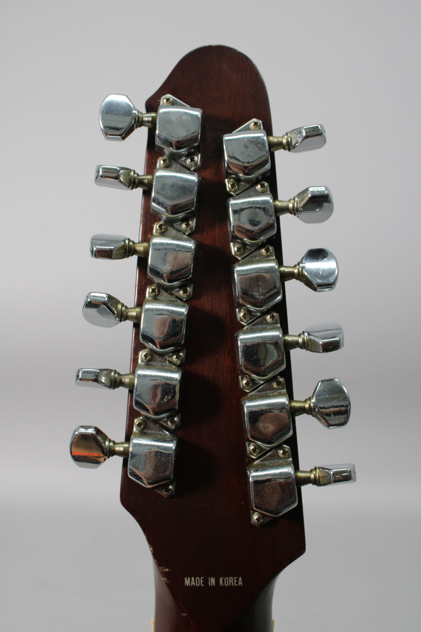 Rear view of the dark brown headstock, showing twelve chrome tuners in two rows, with some tarnishing and minor wear.
