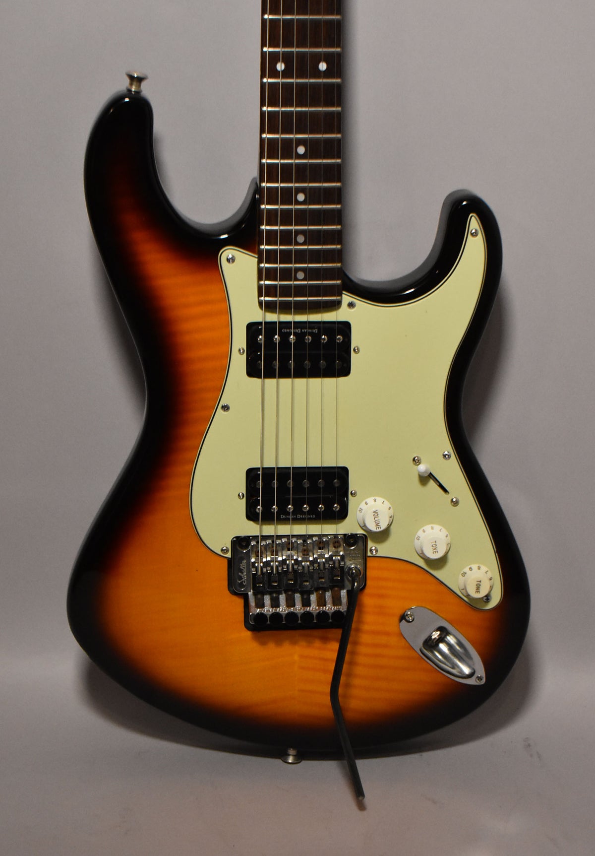 Full front view of a sunburst electric guitar with a cream pickguard, two humbucker pickups, a tremolo bridge, and three white control knobs.