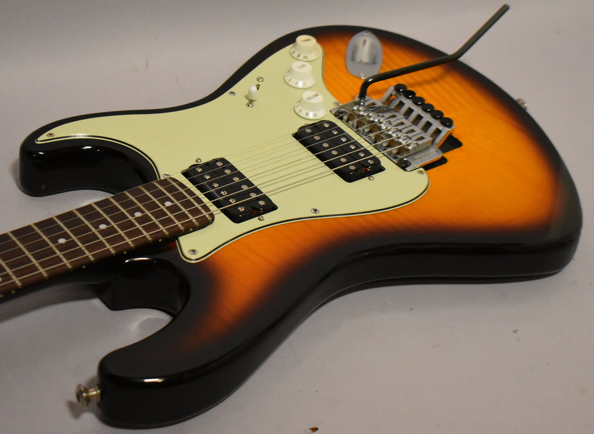 Sunburst S-style guitar, angled from the lower bout, showing the cream pickguard, two humbuckers, and chrome Floyd Rose tremolo.
