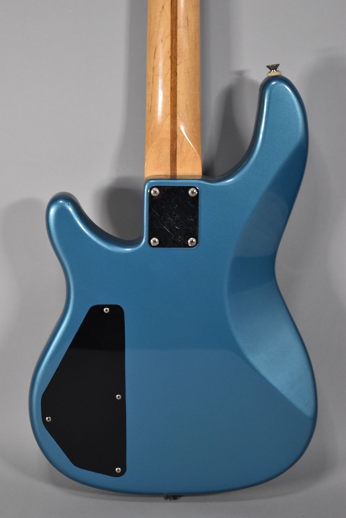 The bass's Lake Placid Blue body, with a maple neck and black control plate, is shown from the back, with light wear on the neck plate.