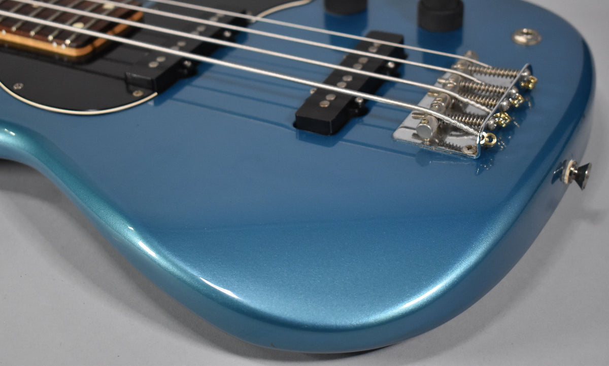 Close-up of the bass body, showing the metallic Lake Placid Blue finish, black pickguard, bridge, and two pickups.