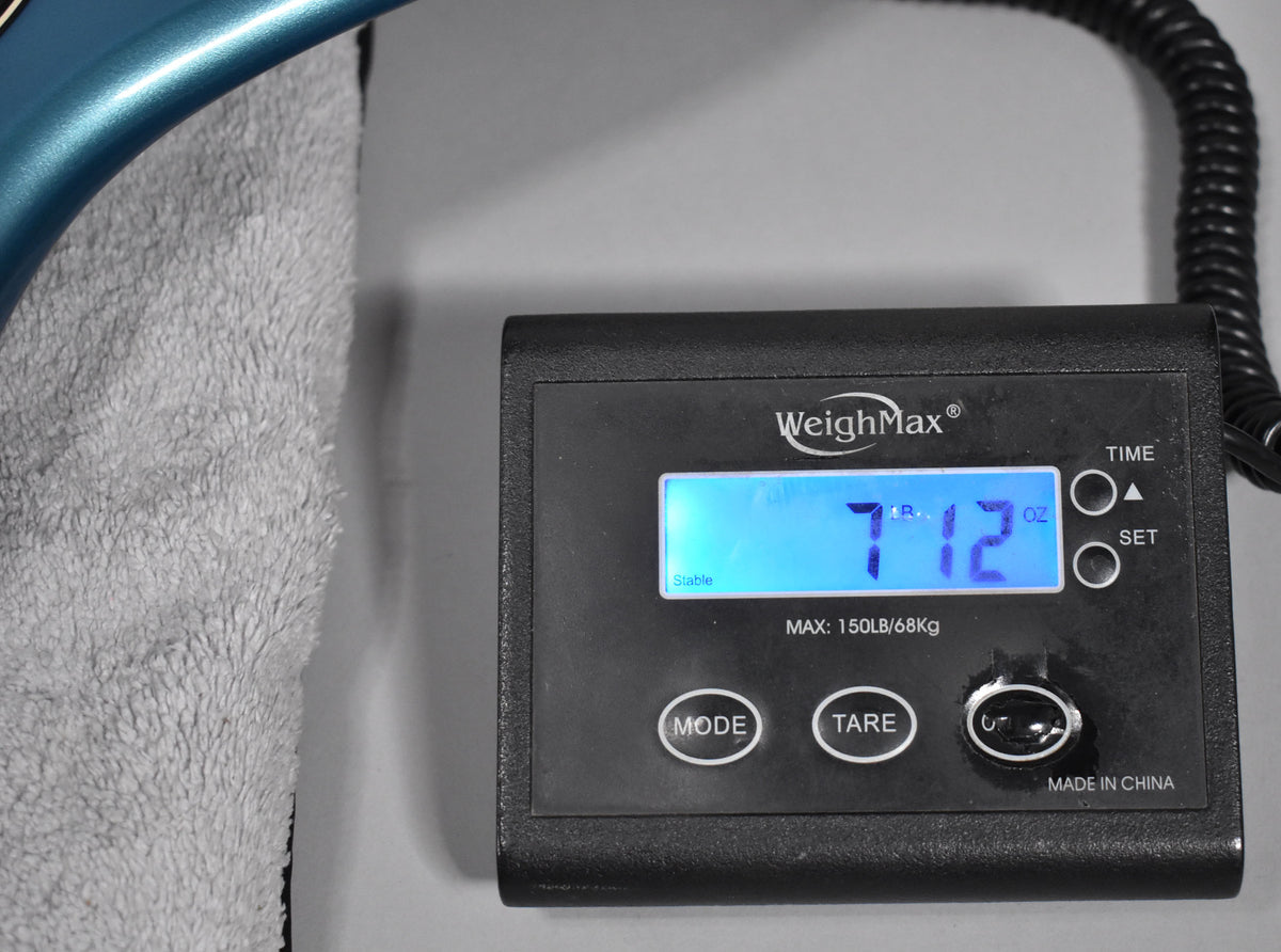 The bass's Lake Placid Blue body rests on a towel next to a digital scale displaying "7 LB 12 OZ".