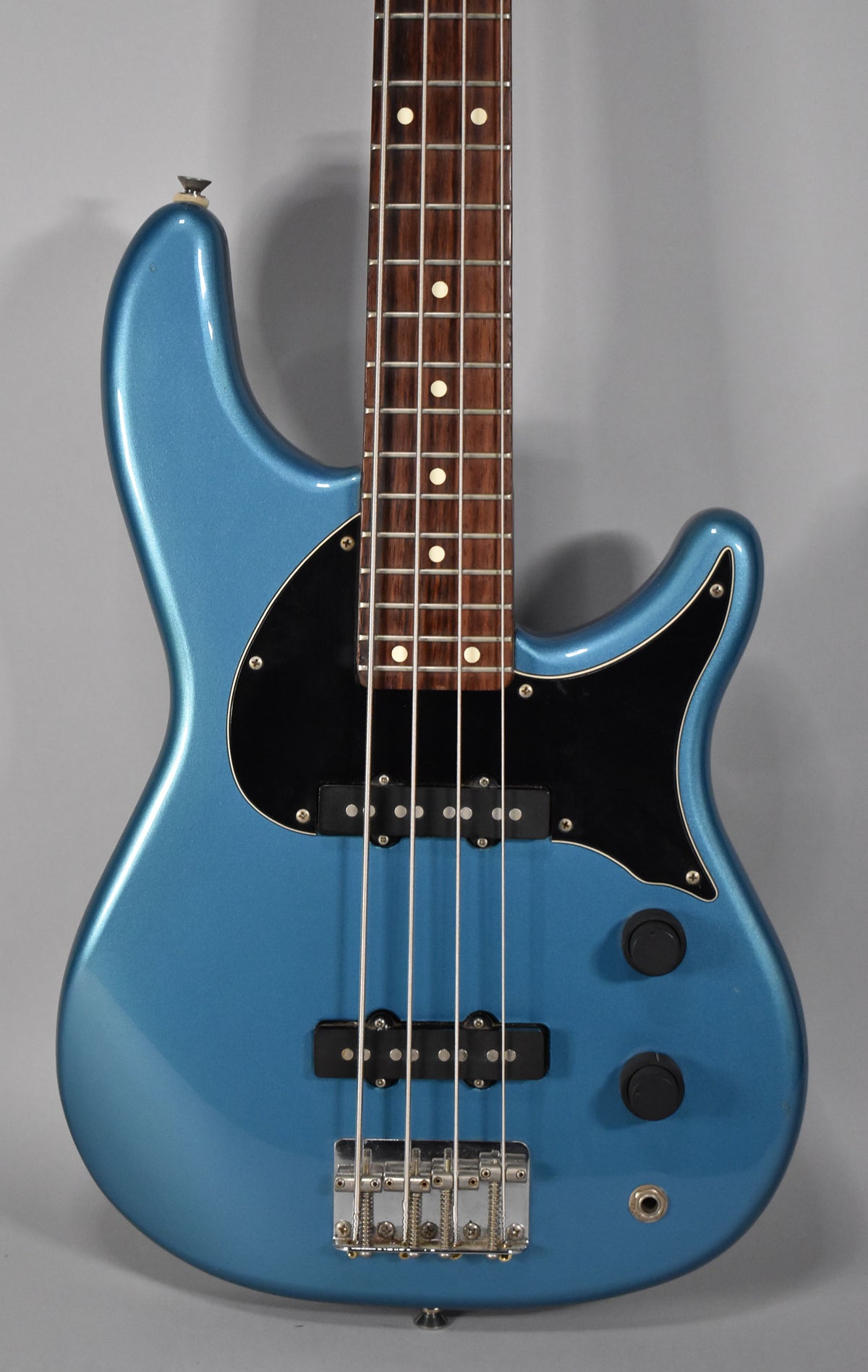 The Lake Placid Blue bass is shown from the upper body to the lower bout, with a black pickguard, two pickups, and two control knobs.