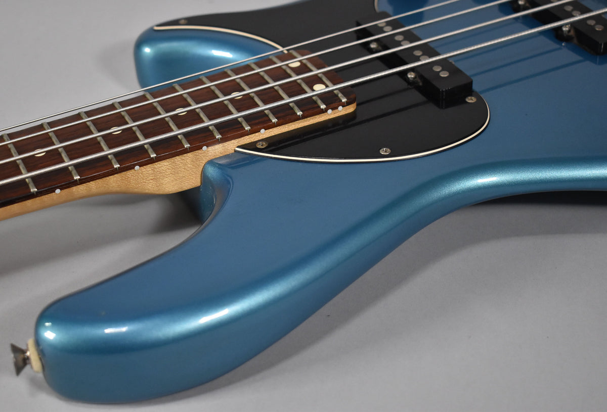 The Lake Placid Blue bass body, with a black pickguard and two pickups, is shown from the lower bout, angled towards the neck.