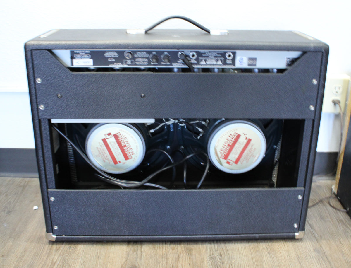 Rear view of a black textured combo amp, revealing two large Jensen speakers and the top-mounted control panel.